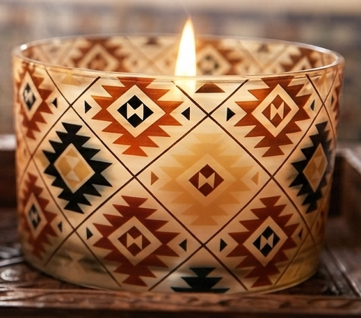 Gros plan d’une bougie allumée à motifs géométriques terracotta, noirs et crème 